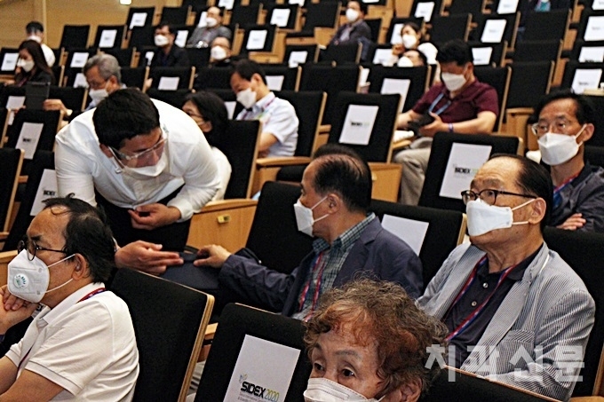 안내요원이 강연장에 입실한 참가자에게 좌석 간 간격 두고 앉기를 안내하고 있다.