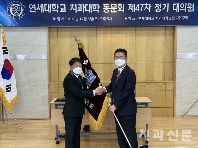 강충규 회장(좌)이 김선용 신임회장에게 연세치대동문회기를 넘겨주고 있다.