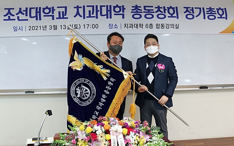 조선치대총동창회 권훈 회장(사진 좌)이 홍성수 신임회장(사진 우)에게 동창회기를 전달하고 있다.