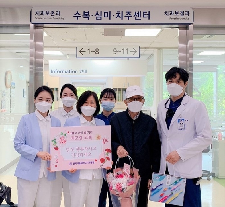 어버이날을 맞이해 김재영 진료부장(사진 오른쪽)과 김명희 파트장(사진 왼쪽에서 세번째)이 치과보철과에 내원한 최고령 환자 정기영(87세)씨에게 꽃다발과 기념품을 전달하고 있다.