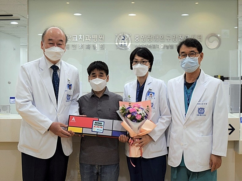 개소 2주년을 맞이한 서울대치과병원 중앙장애인구강진료센터. 지난 23일 서울대치과병원 구영 원장(사진 좌), 금기연 센터장(사진 우), 유수연 교수(사진 가운데)가 첫 번째 내원한 환자에게 꽃다발과 기념품을 전달했다.